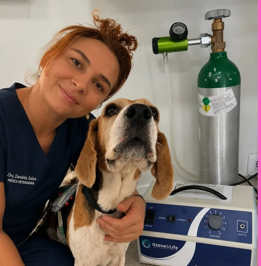 Dra. Daniela com um beagle ao lado do aparelho de ozonioterapia